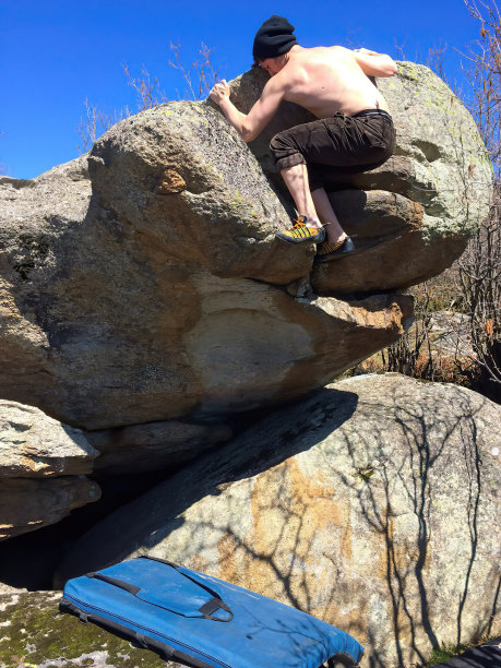 一名年轻男子在户外攀爬巨石图片下载