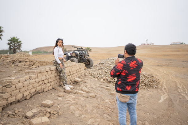 一名男子正在拍摄一名女子站在户外四合院旁的照片图片下载