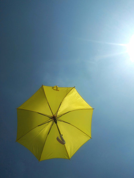 飞行的黄色伞与蓝天的背景图片下载