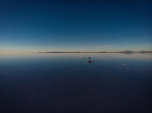 旅游团与越野车在乌尤尼盐沼湖在玻利维亚安第斯山脉日出镜面反射图片下载
