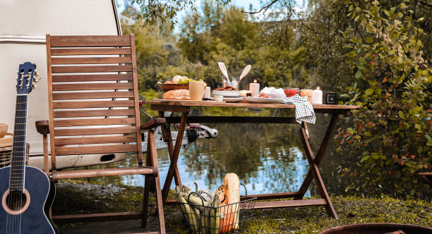 在大自然中野餐。木制椅子、桌子。烧烤BBQ BBQ食物。全家度假旅游，度假周末聚餐。路上的午餐小吃。用露营车，带轮子的房子，拖车房车旅行。营地在一夜之间图片下载
