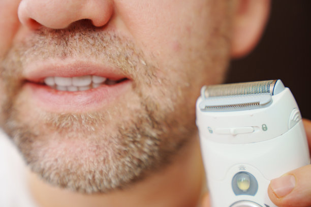 特写镜头。一个拿着电动剃刀的男人图片下载