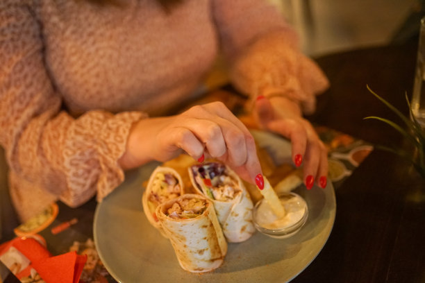 女人在餐厅吃饭，特写照片，注意手和食物。图片下载
