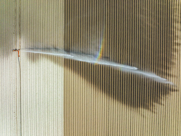 在一个干燥温暖的春日里，喷灌机在田间喷水。图片下载