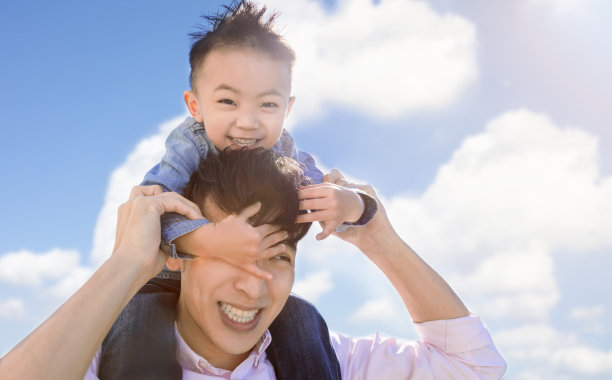 快乐的父亲背着小男孩在公园里玩耍图片下载