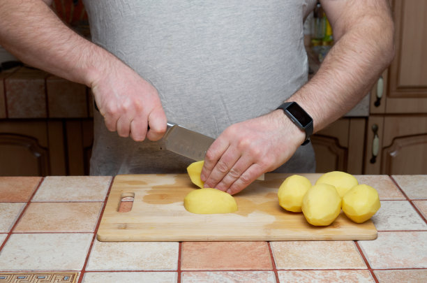烹饪。在砧板上切生土豆图片下载