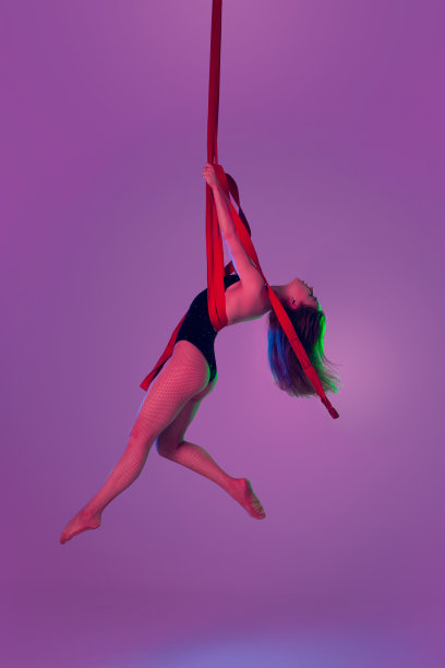 身着黑色泳装的漂亮女孩正在工作室里表演杂技元素。图片下载