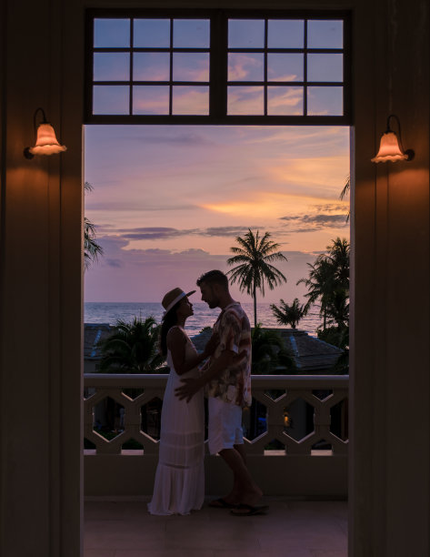 在热带岛屿度假时，一对年轻男女在游泳池边看日落图片下载