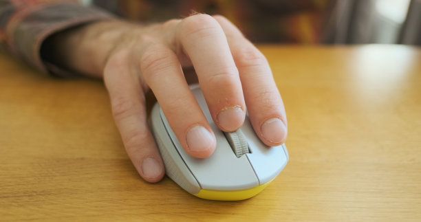 人的手开始用电脑鼠标工作。正面，特写。点击按钮，用滚轮滚动。木质桌面图片下载