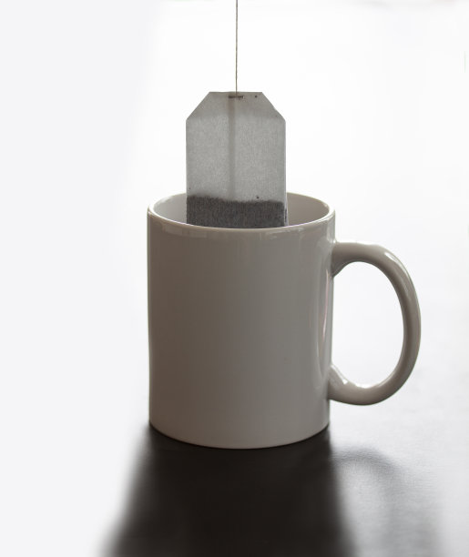 白色的杯子放在桌上，茶包用绳子挂着图片下载