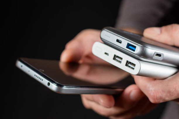 男子手持智能手机和充电宝充电器。静物现代数字概念。图片下载