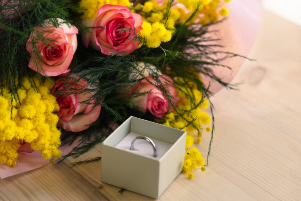 顶视图的结婚戒指在一个盒子，两束玫瑰和含羞草在木桌上图片下载