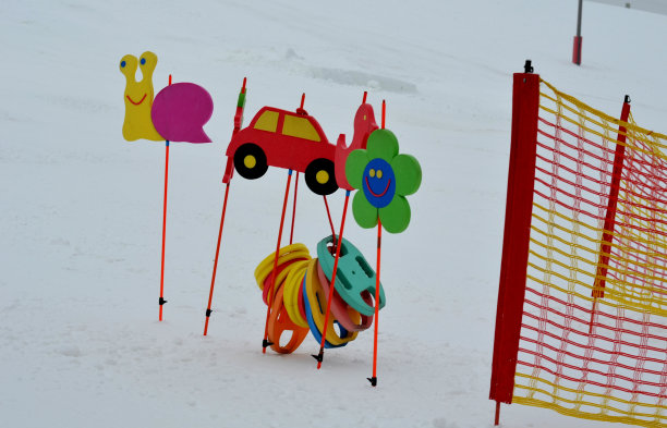 斜坡上保护儿童比赛观众的塑胶安全网。有快乐动物的泡沫图片，以纪念滑雪学校的障碍滑雪。树枝被困在雪里了图片下载