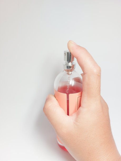 女性手拿白色背景的香水瓶图片下载