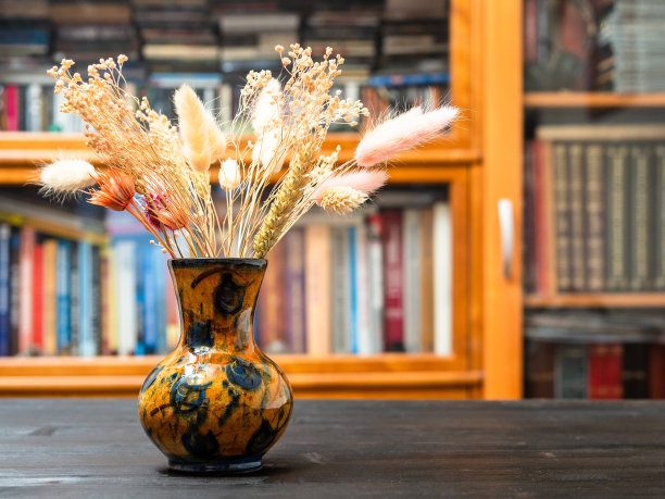 深色桌子上有书架的花瓶里有干燥的植物图片下载