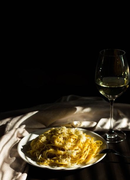 意大利面加奶酪和黑胡椒。一杯白葡萄酒。图片下载
