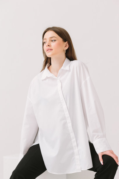 一个穿着白衬衫的漂亮女人坐在白色立方体上的照片，孤立在白色背景上。衬衫模型。图片下载