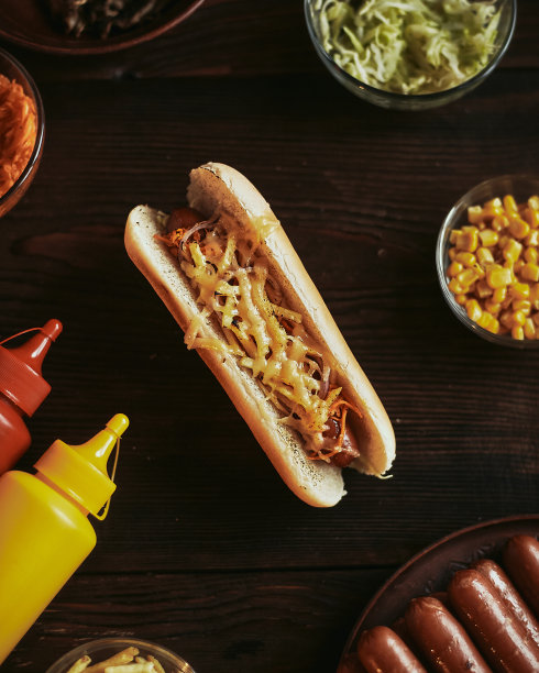 热狗放在木板上。木桌上放着香肠、奶酪和芥末的美式快餐。照片从顶部。图片下载