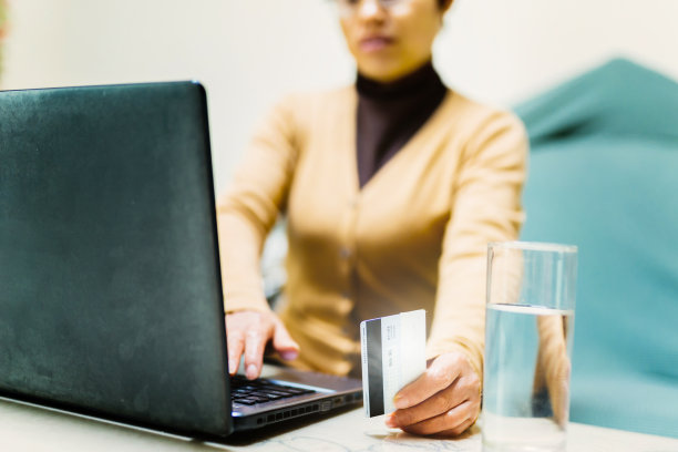 一位中年妇女正在家里用信用卡购物——技术与生活、信用卡、银行与支付的概念图片下载