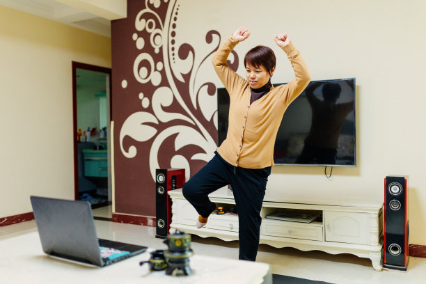 一位中年妇女在瑜伽垫上用笔记本电脑学习健身之道——科技与生活，健康的生活方式图片下载