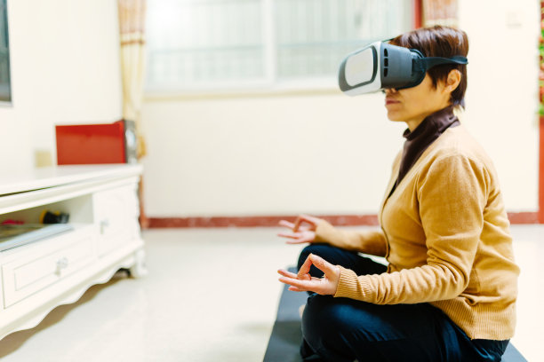 一位中年妇女带着VR眼镜在家学习瑜伽——科技与生活，健康的生活方式图片下载