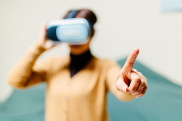 一位中年妇女沉浸在VR眼镜的沙发上——科技与生活，健康的生活方式图片下载