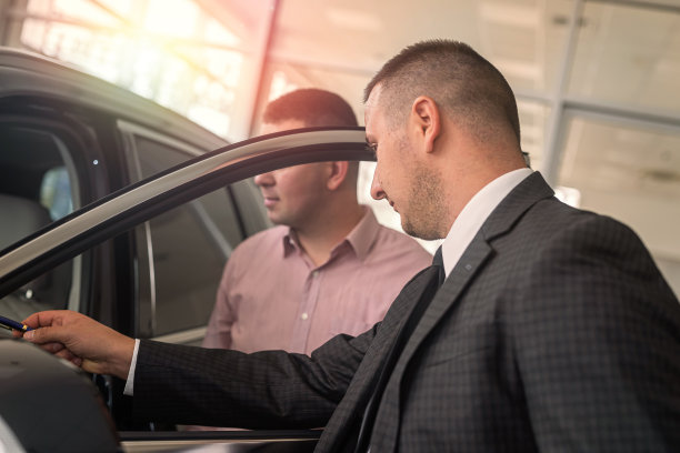 年轻男性客户坐在新车内，在展厅与主管经理交谈图片下载