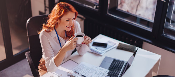 高角度视角的休闲年轻女商人喝咖啡休息和放松在办公室。图片下载