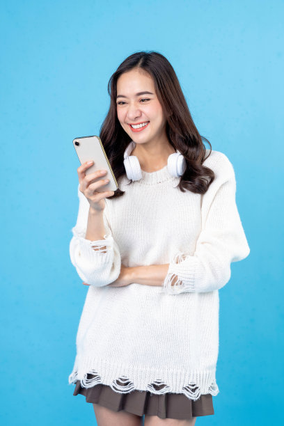 快乐的亚洲女商人使用手机隔离在浅蓝色背景。女性手中的智能手机黑屏。图片下载