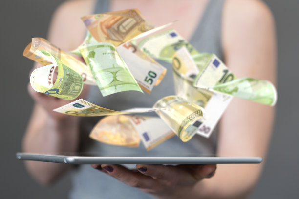 一名女性手持的平板电脑上漂浮着欧元纸币图片下载