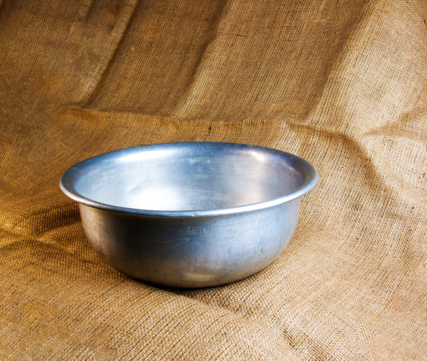 一个1960年左右制作的旧铝碗，背景是粗麻袋。图片下载