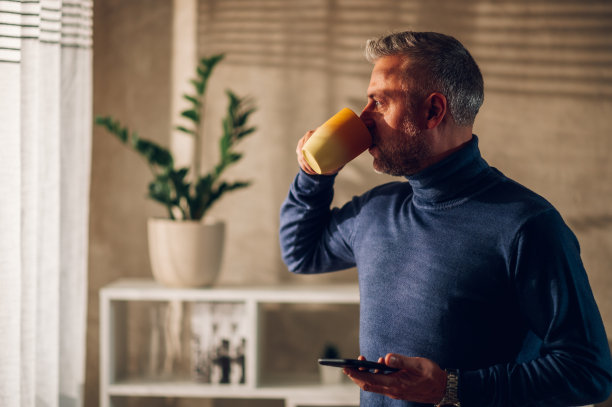 中年男子在家里用智能手机喝咖啡图片下载