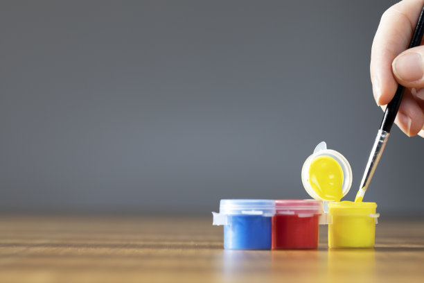 艺术家用彩色油漆刷在木桌上，以灰色为背景，复制空间蓝色、红色和黄色图片下载