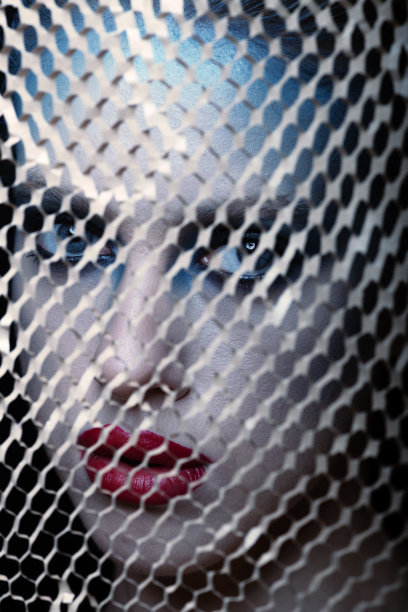 抽象的工作室肖像美丽的女人与花哨的化妆看透过棕色网格图片下载