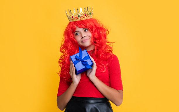 高兴的孩子在皇冠上与礼品盒上的黄色背景图片下载