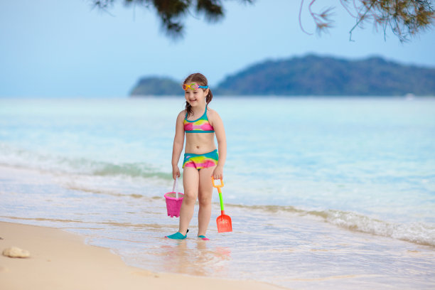 孩子们在热带海滩上玩耍。沙子和水的玩具。图片下载