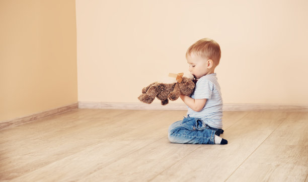 可爱的男孩坐在室内的地板上。图片下载