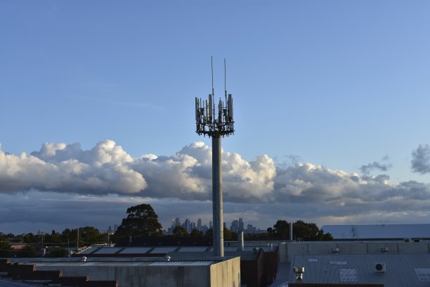 蓝天下的5G手机塔，远处是一座城市。图片下载