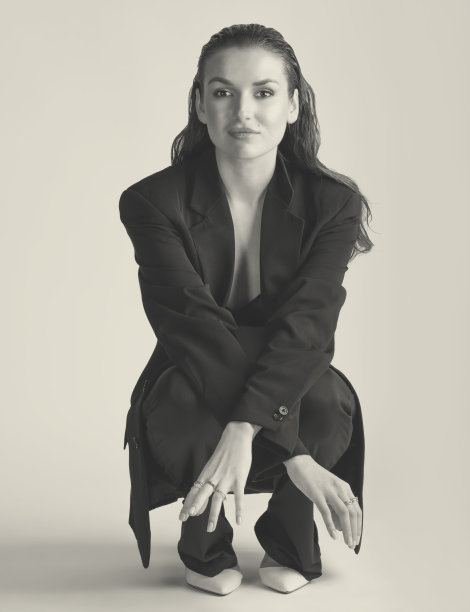 工作室肖像美丽的女人与黑色西装和湿头发蹲在地板上图片下载