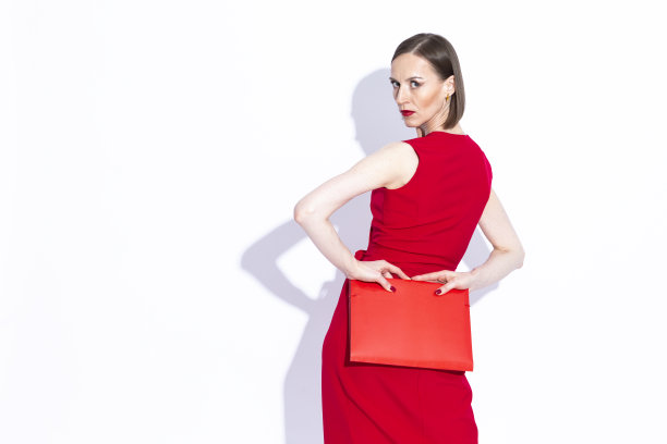 性感的肖像迷人集中自信的白人女商人在红色连衣裙摆出挑衅的姿态与红色文件夹在白色图片下载