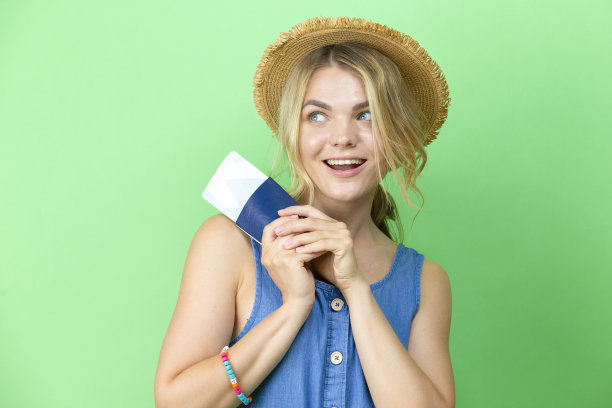 旅行的想法。梦想迷人的可爱的微笑年轻女孩在草帽和蓝色连衣裙拿着护照与票新潮的绿色背景图片下载