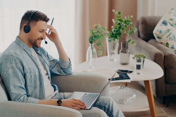 微笑的帅哥盯着笔记本电脑屏幕在家里图片下载