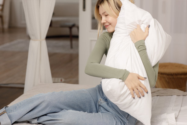 放松的年轻女子拥抱枕头在床上。健康的睡眠。图片下载