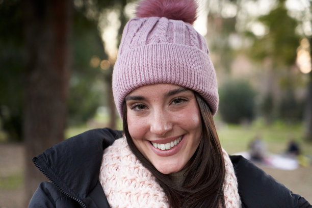 肖像美丽的微笑年轻的白人妇女与冬季帽子看着相机积极的表情图片下载