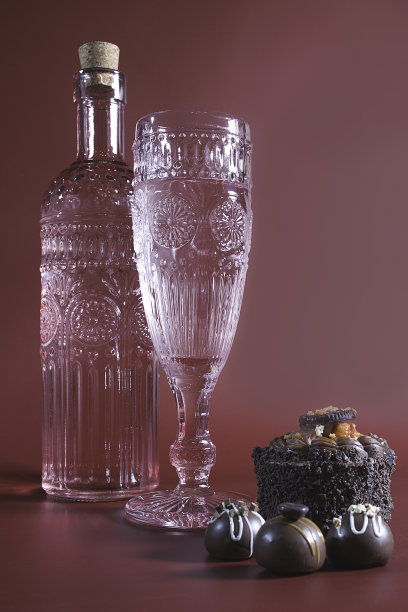 巧克力甜点颓废:一杯复古香槟，巧克力蛋糕和糖果在粉红色的背景图片下载