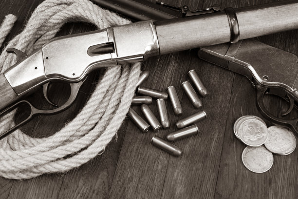 老西部枪-杠杆动作连发步枪弹药和银币。深褐色的基调。图片下载