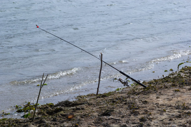 钓鱼竿和渔具放在河堤上，湖岸近距离收浪图片下载