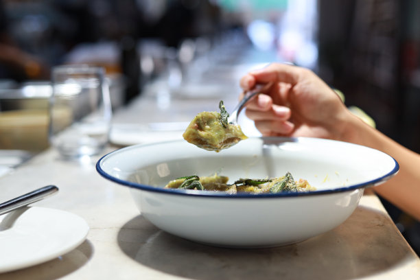 裁剪图片的女人享受菠菜agnolotti馅摩泰台拉和乳清干酪与柠檬皮黄油酱在餐厅图片下载