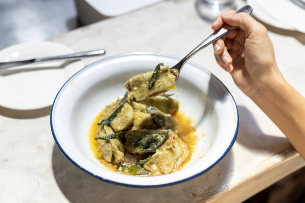 裁剪图片的女人享受菠菜agnolotti馅摩泰台拉和乳清干酪与柠檬皮黄油酱在餐厅图片下载