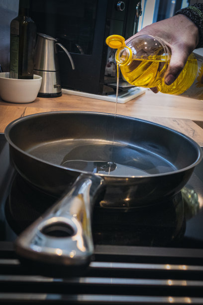 锅在炉子上，一瓶油倒了进来。图片下载